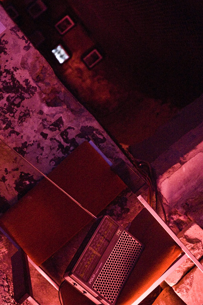 Ein Kofferradio auf einem Stuhl vor einer unverputzten Wand.